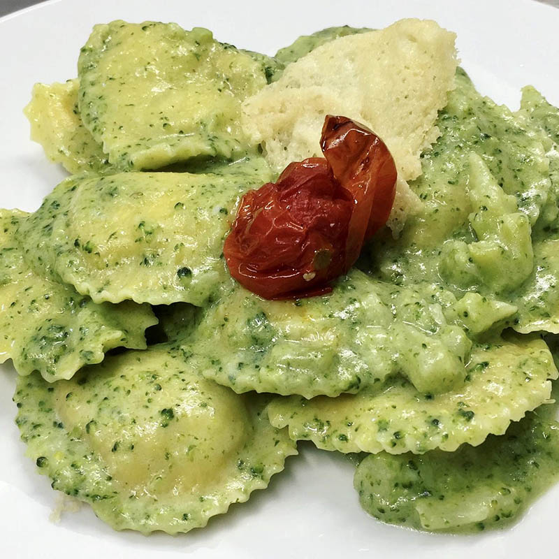 Raviolo di ricotta e spinaci con pesto, pomodorino arrosto e scaglia di parmigiano